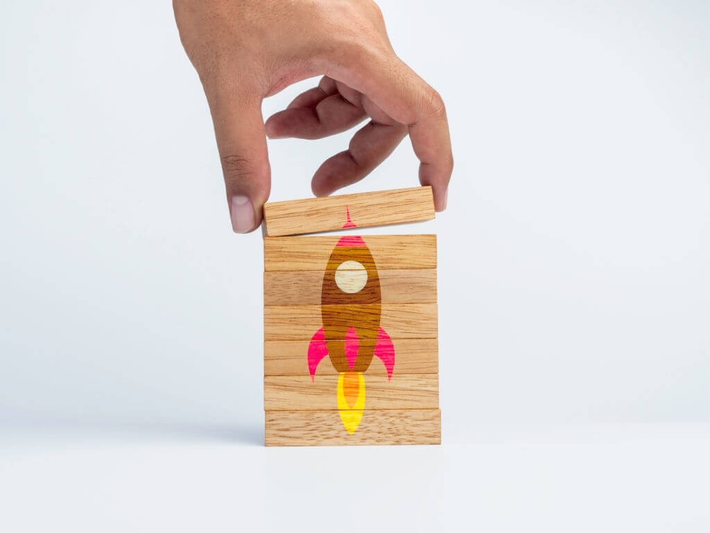 Person assembling a rocket with different wooden blocks